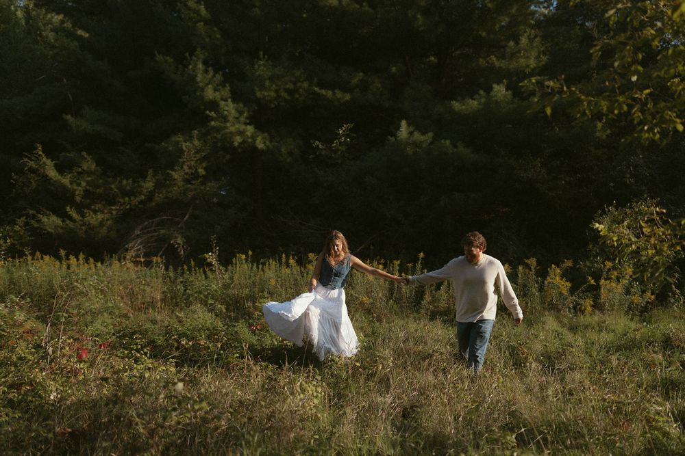 A scenic outdoor photo shoot in a grassy field with evergreen trees.