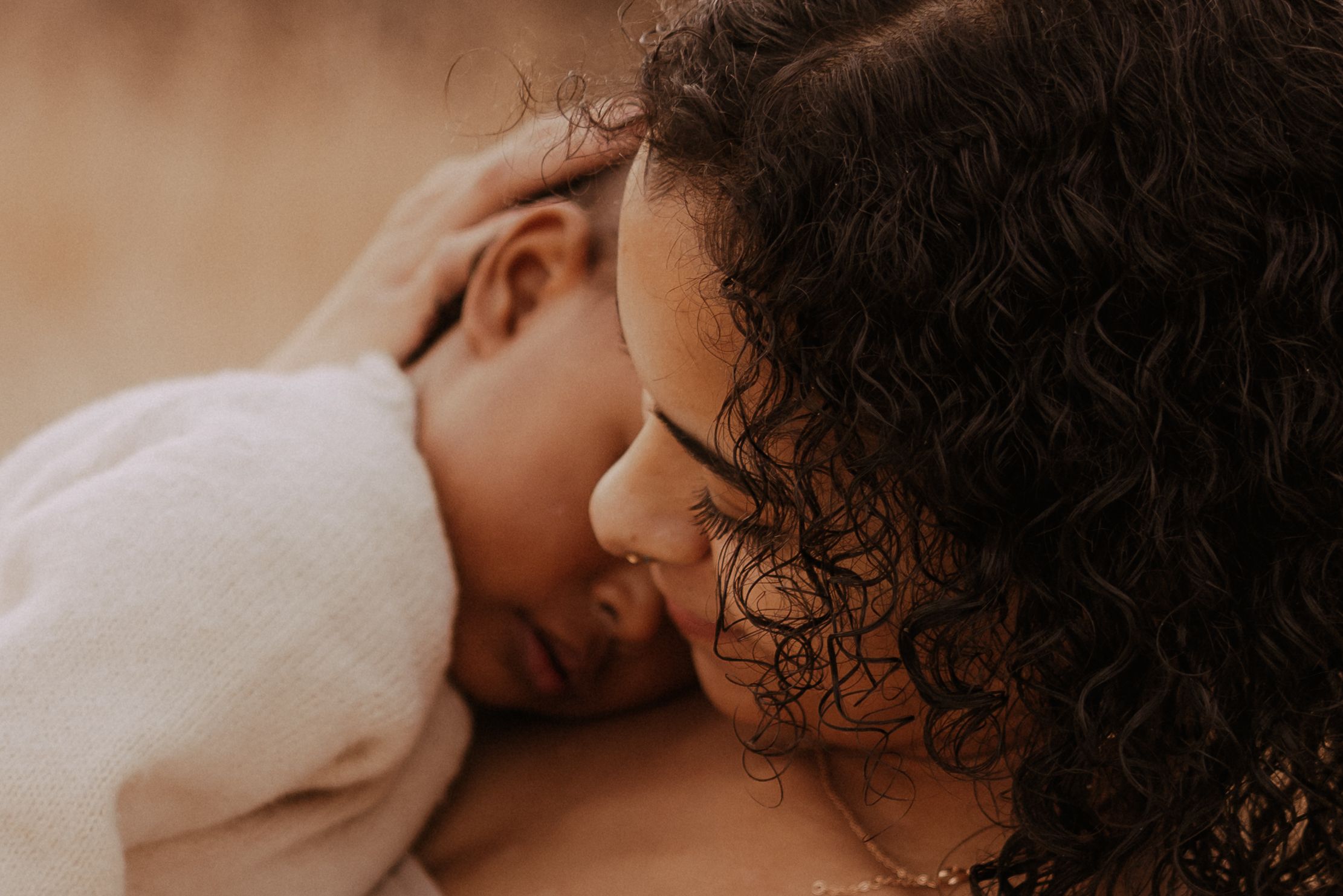 A tender moment between two people sharing a close embrace in soft, warm lighting.