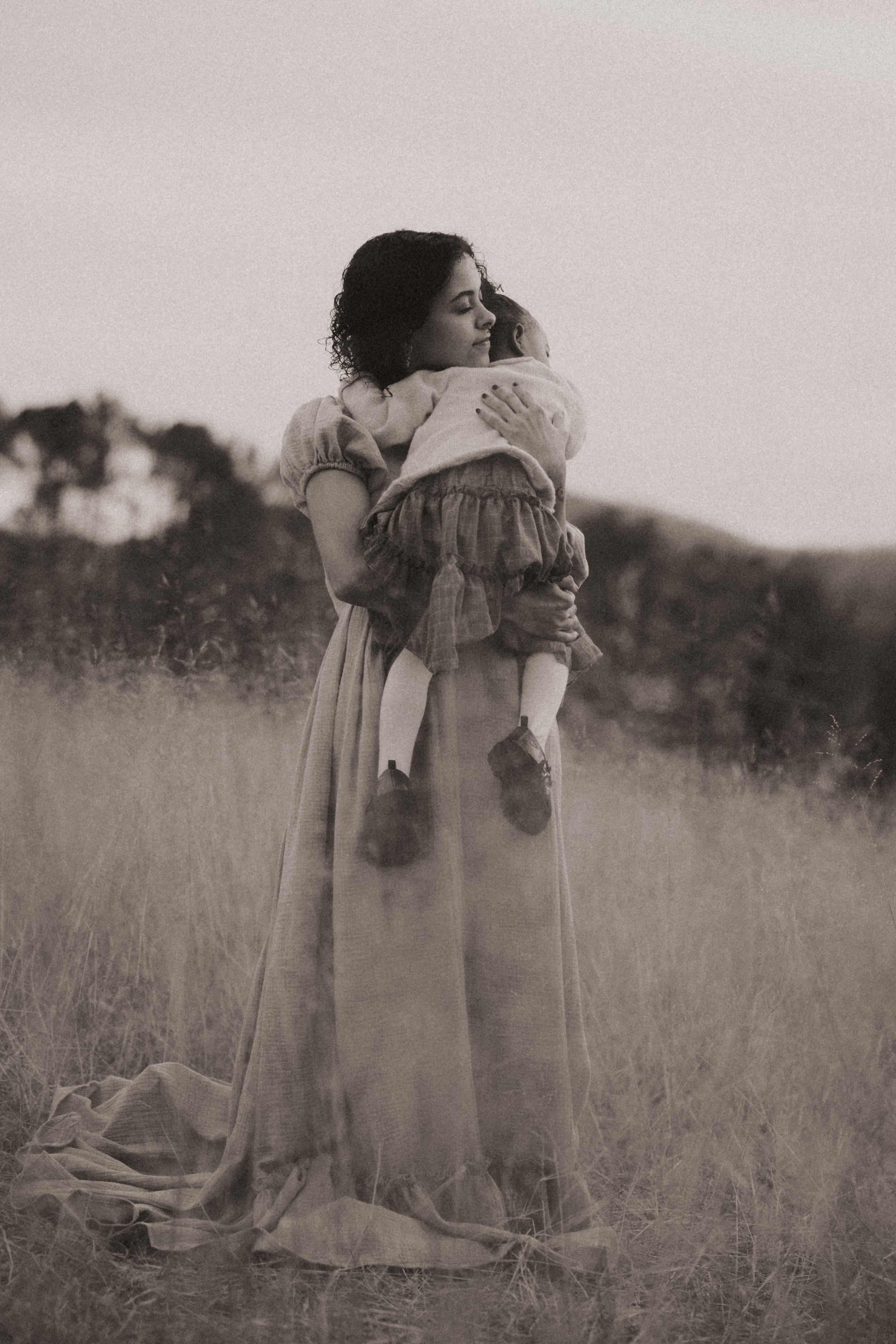 A black and white photo sequence shows a figure in a Victorian dress bending down in a grassy field.