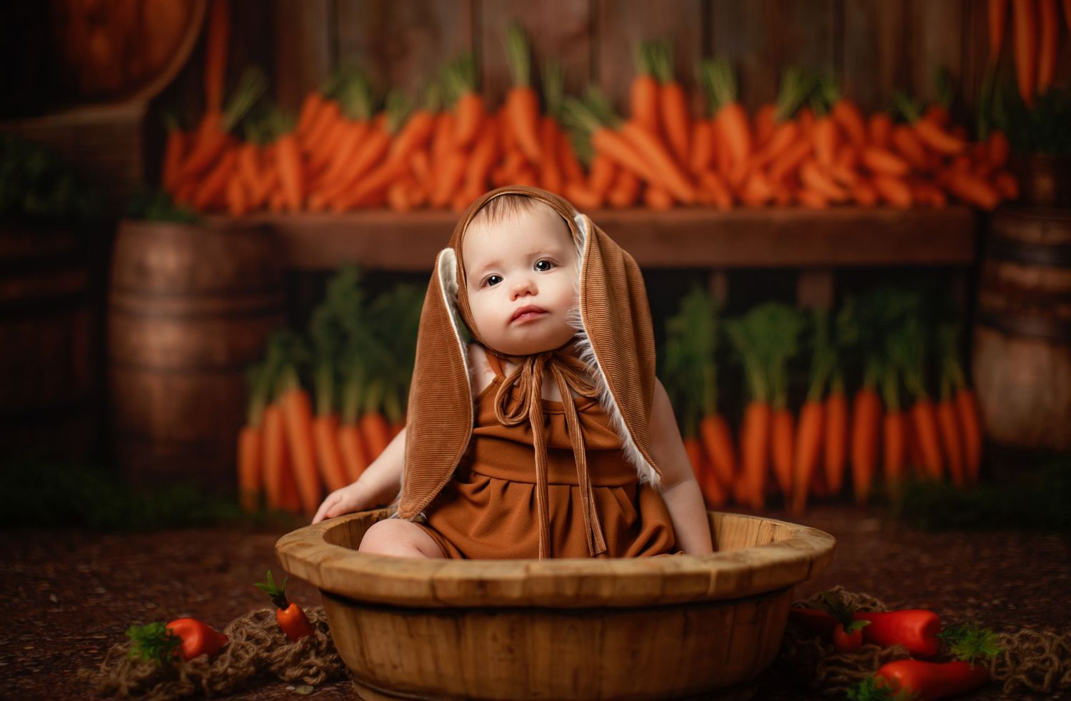 Fresh organic carrots with green tops displayed at farmers market alongside rustic wooden barrels and decorative elements.