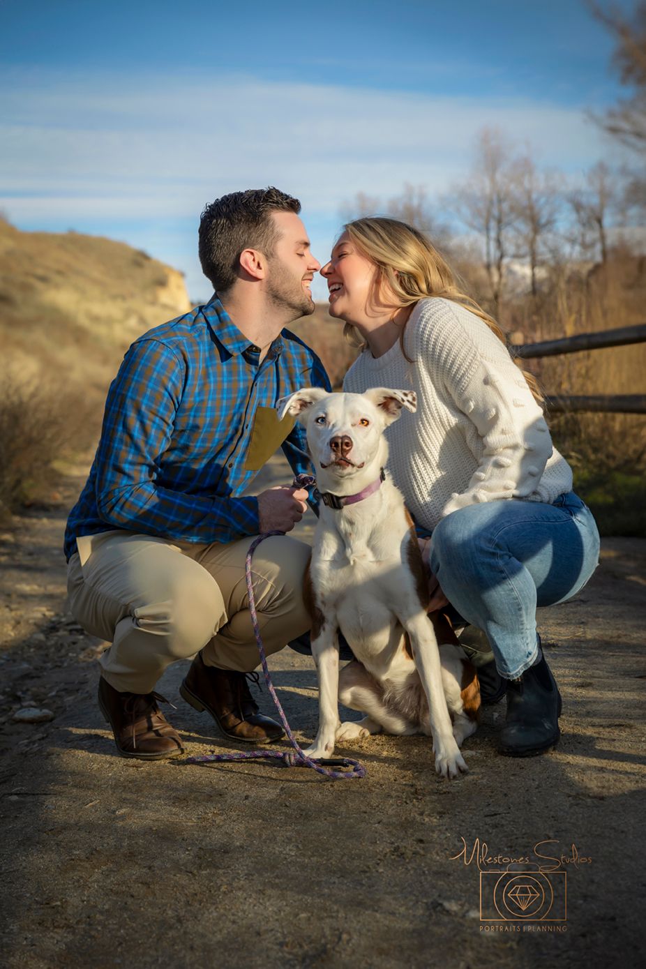 Engagement photo of couple laughing in Boise foothills with their dog