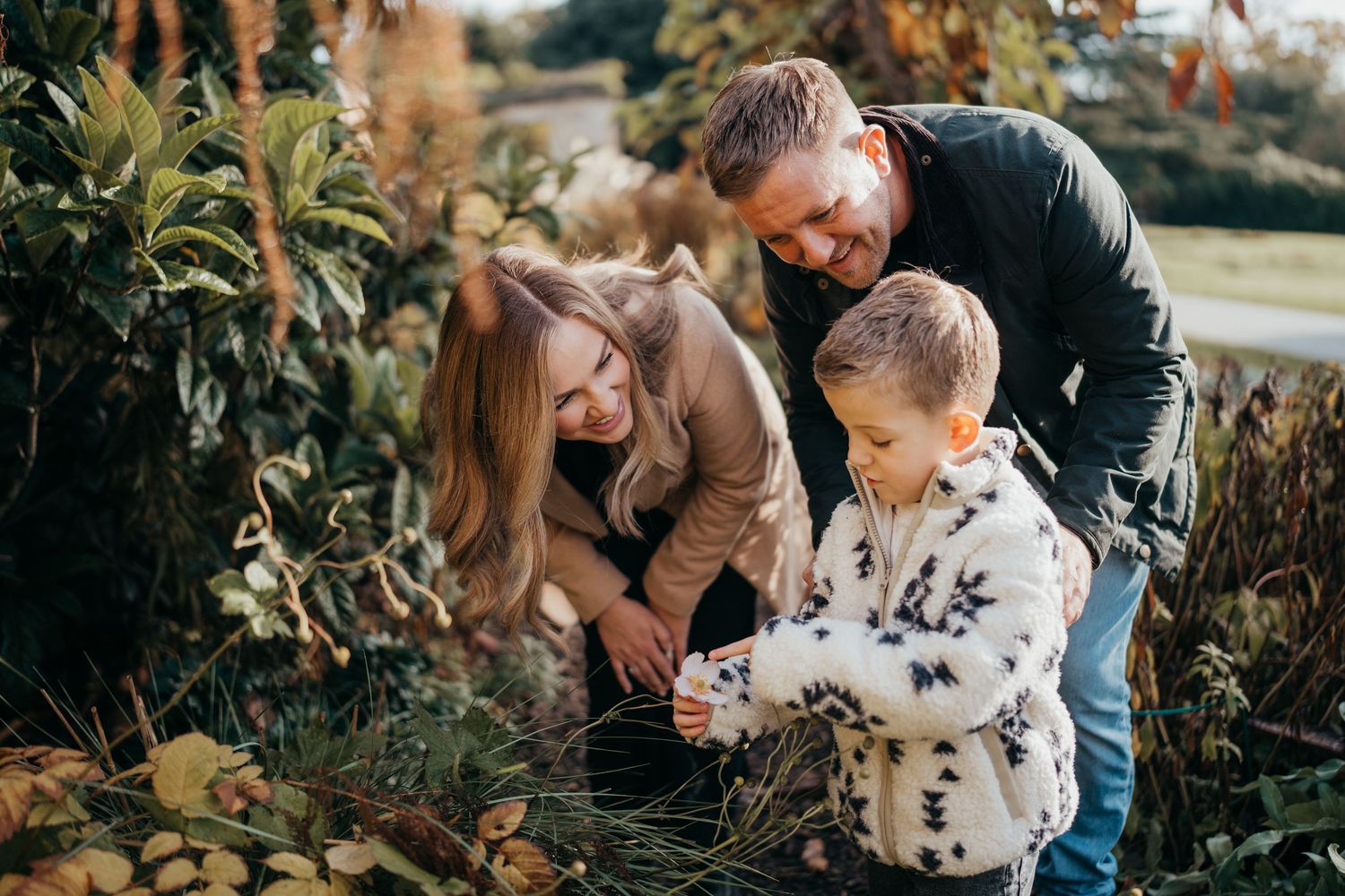 Family shares tender moments together in autumn garden setting.