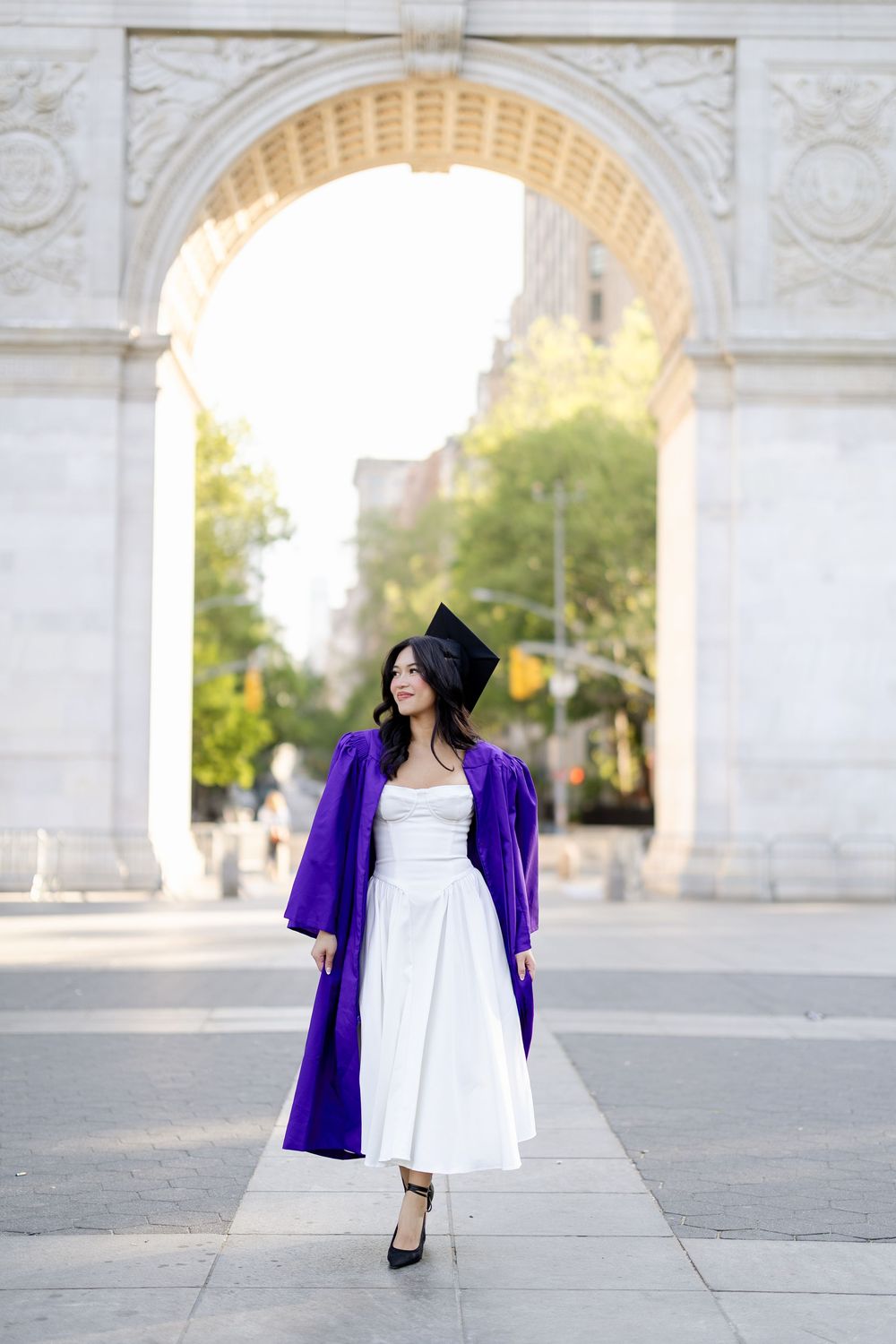 A graduate in white dress and purple graduation gown poses under stone archways in a series of photos.