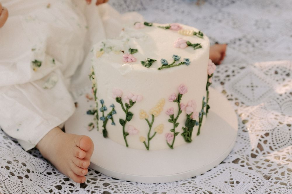 A white lace blanket adorned with delicate flowers and greenery creates a romantic garden scene.