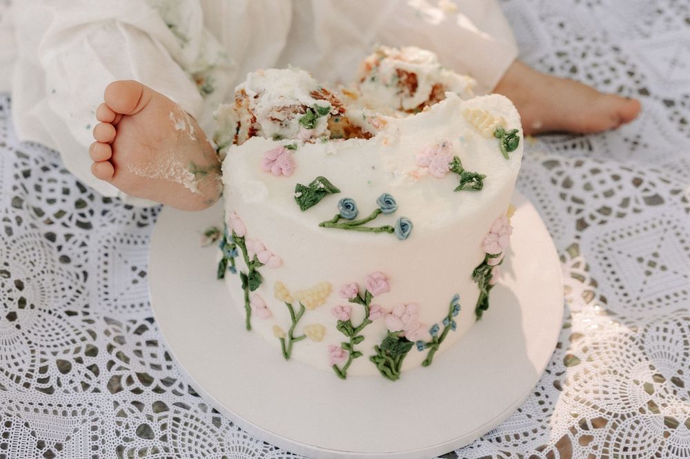 Delicate lace tablecloth with scattered floral decorations and white fabric details in soft lighting.