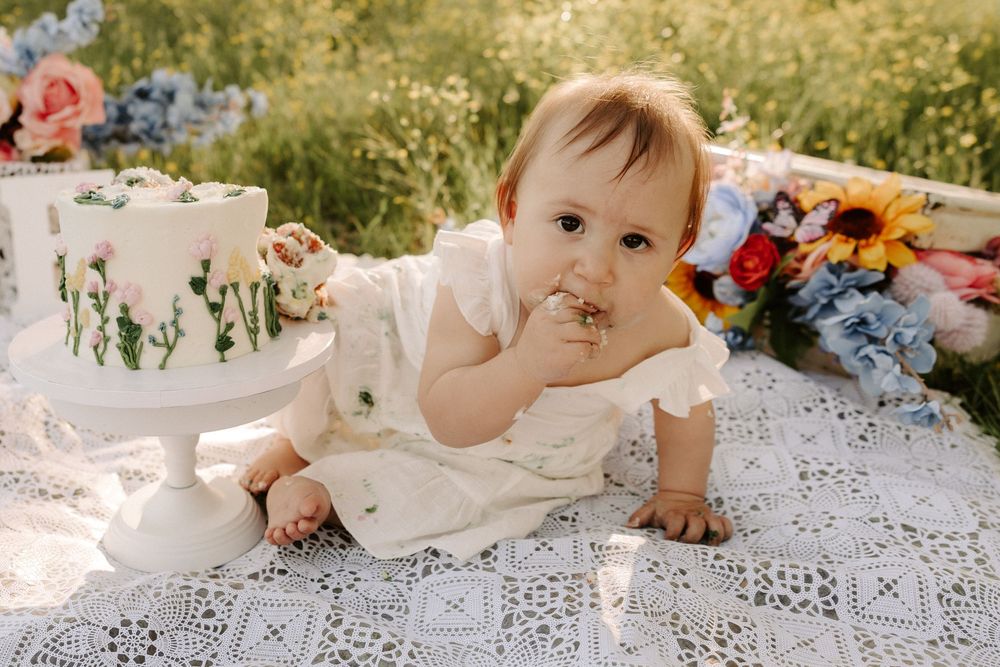 White lace tablecloth spread outdoors with sunlit greenery in the background.