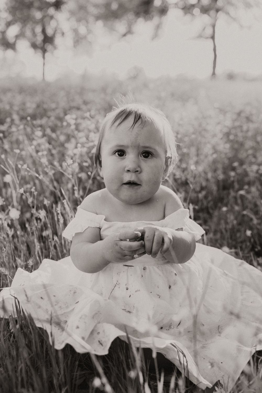 A black and white portrait taken in a wildflower meadow with soft natural lighting.