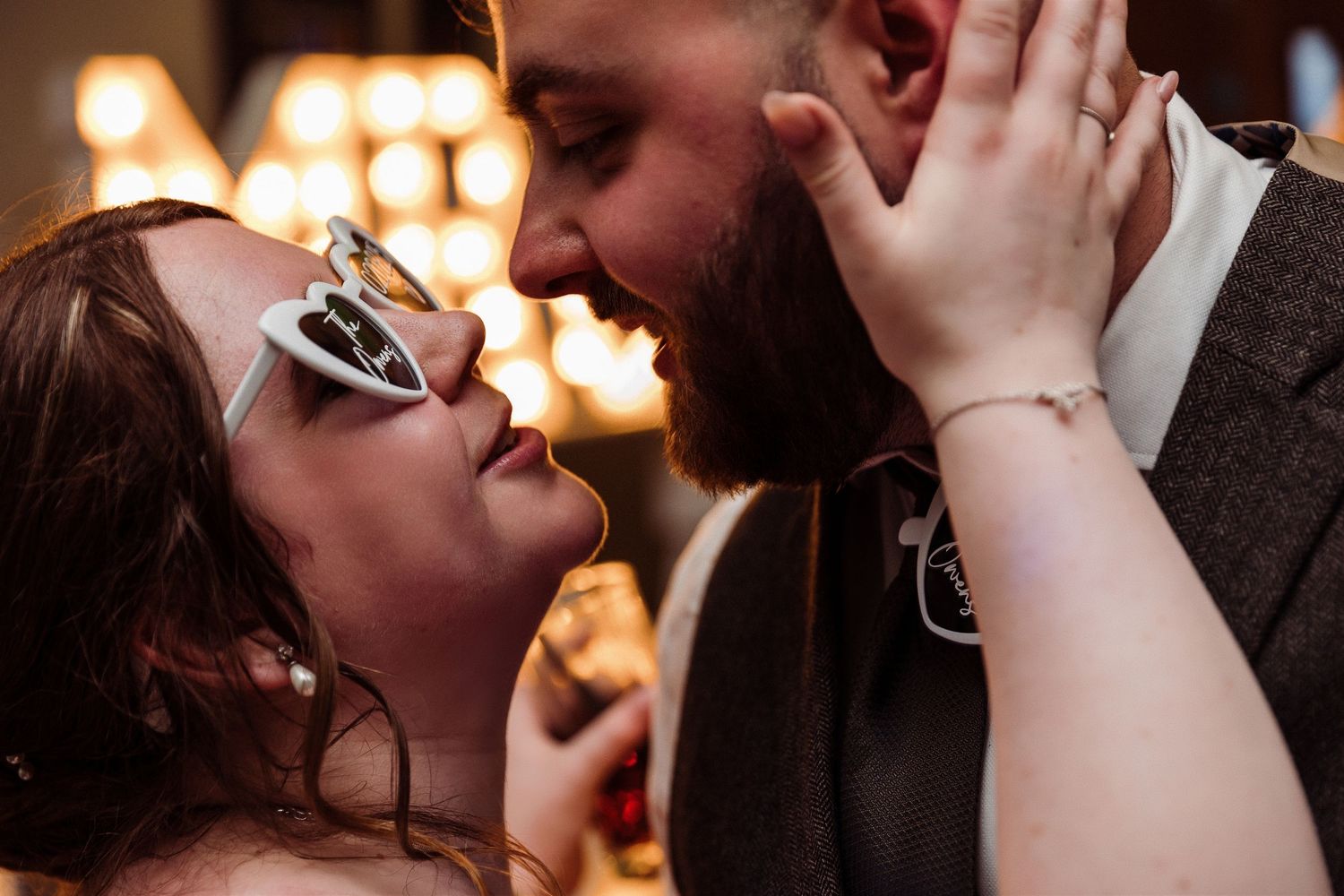People dancing and celebrating at a wedding reception with green lighting and energetic atmosphere on the dance floor.