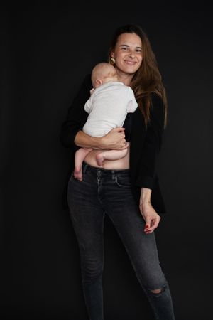 Lachend Mama mit ihrem kleinen Baby auf dem Arm. Familienfotografie Gießen - Coffee and Stories Fotografie