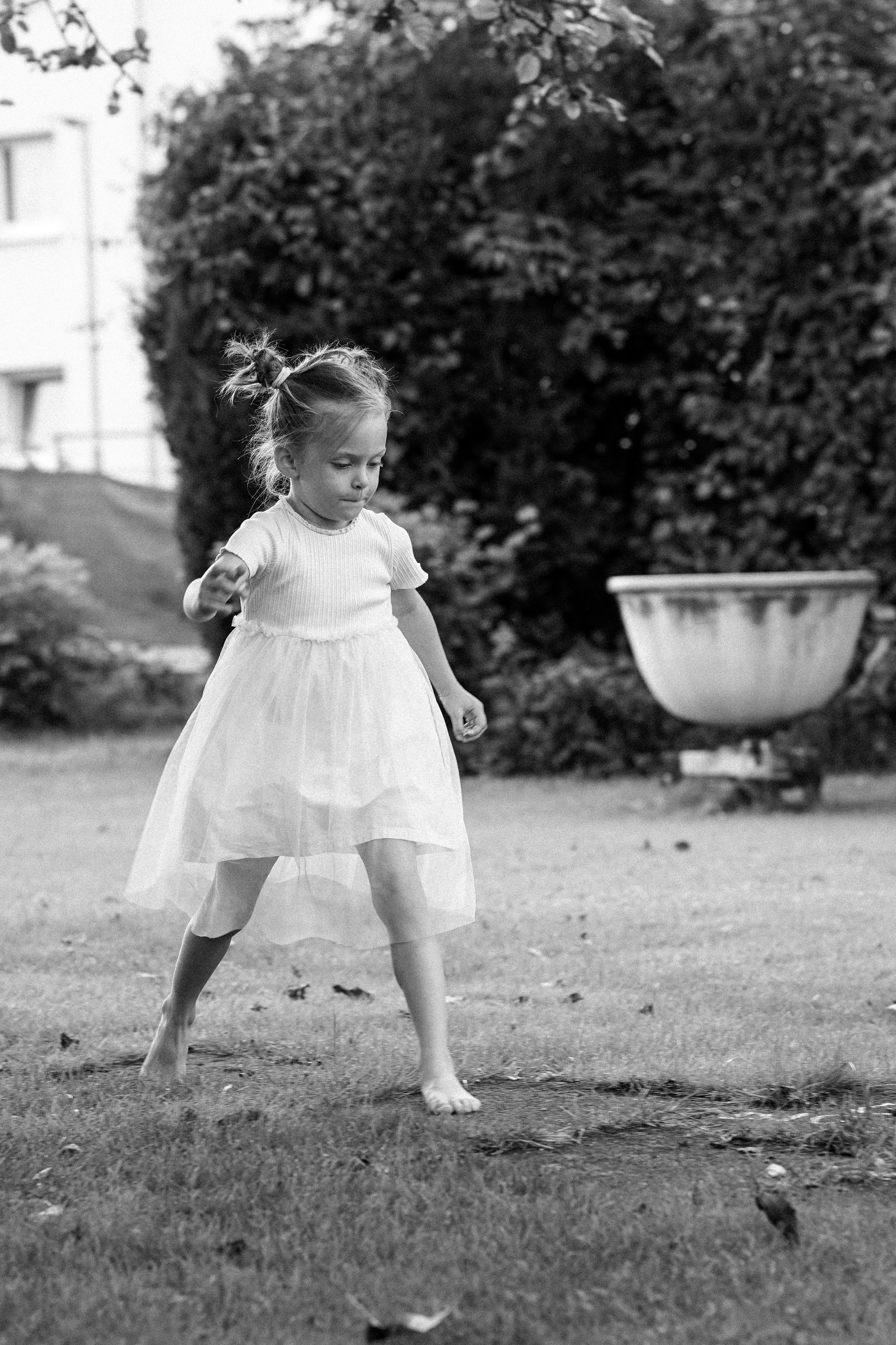 Mädchen hüpft lachend im Sommerkleidchen über die Wiese. Coffee and Stories Fotografie