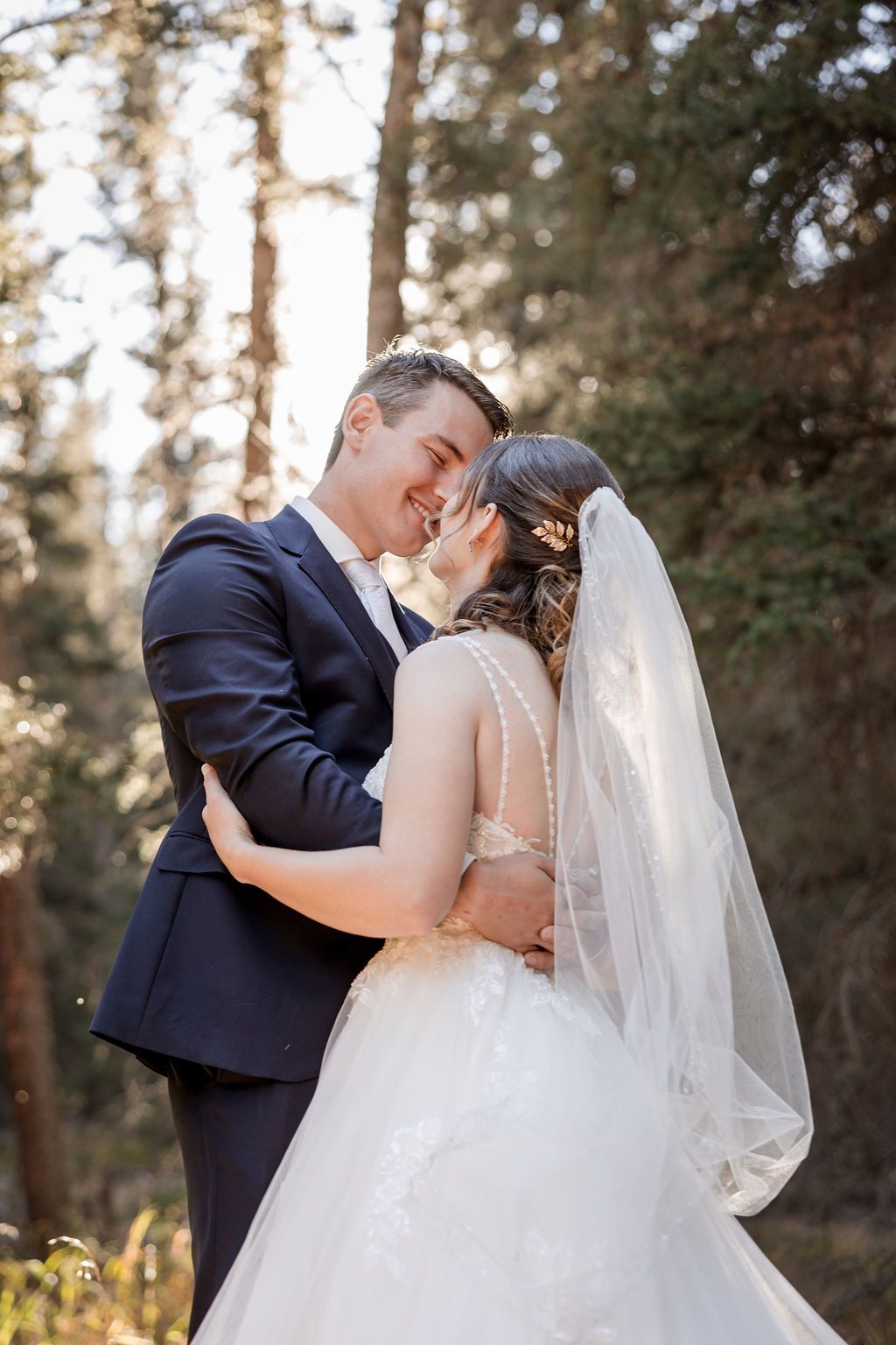 A romantic wedding couple shares intimate kisses in a sunlit forest setting, captured in a series of four photos.