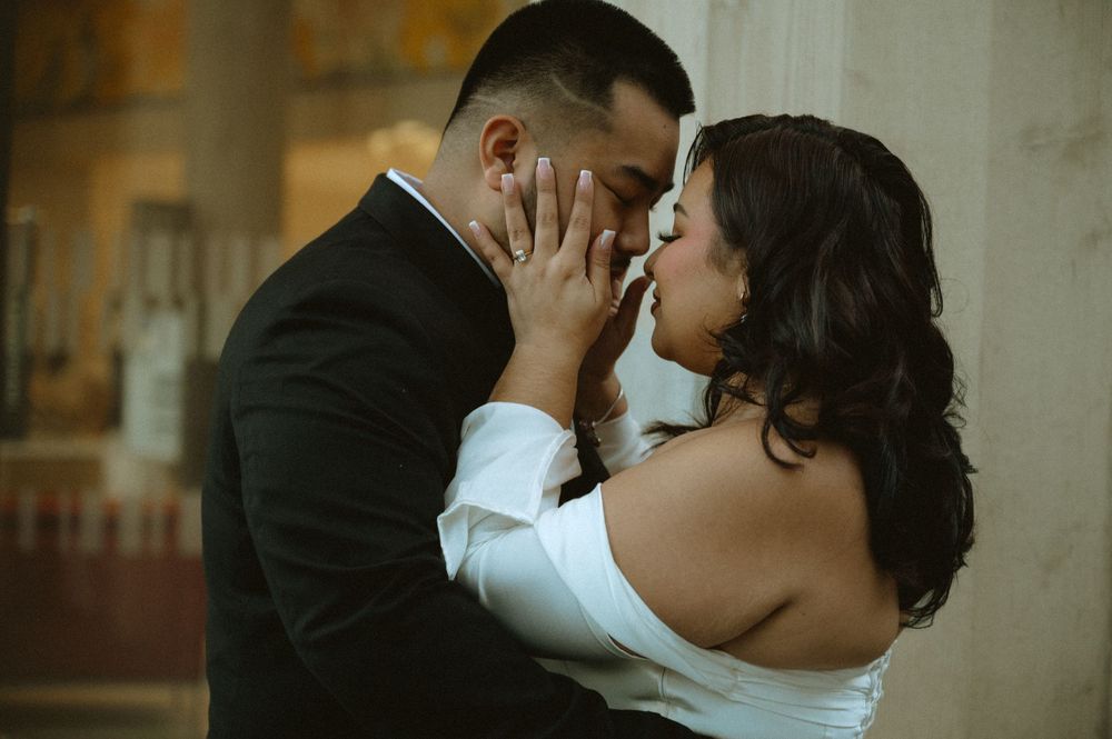 A romantic moment captured outside a building with elegant architectural details.