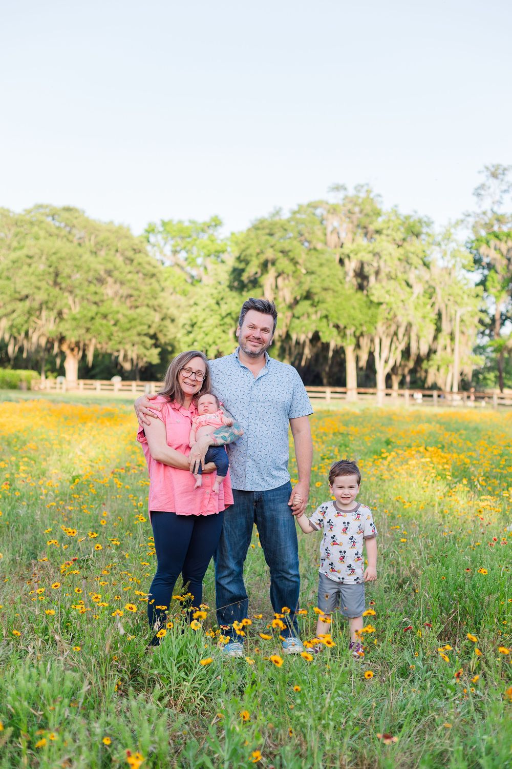 Family standing together in a vibrant wildflower meadow with Spanish moss draped trees in the background.