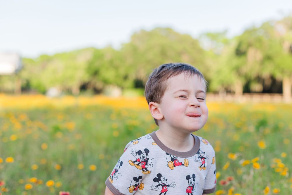 A child plays joyfully in a sunny field of bright yellow wildflowers on a spring afternoon.