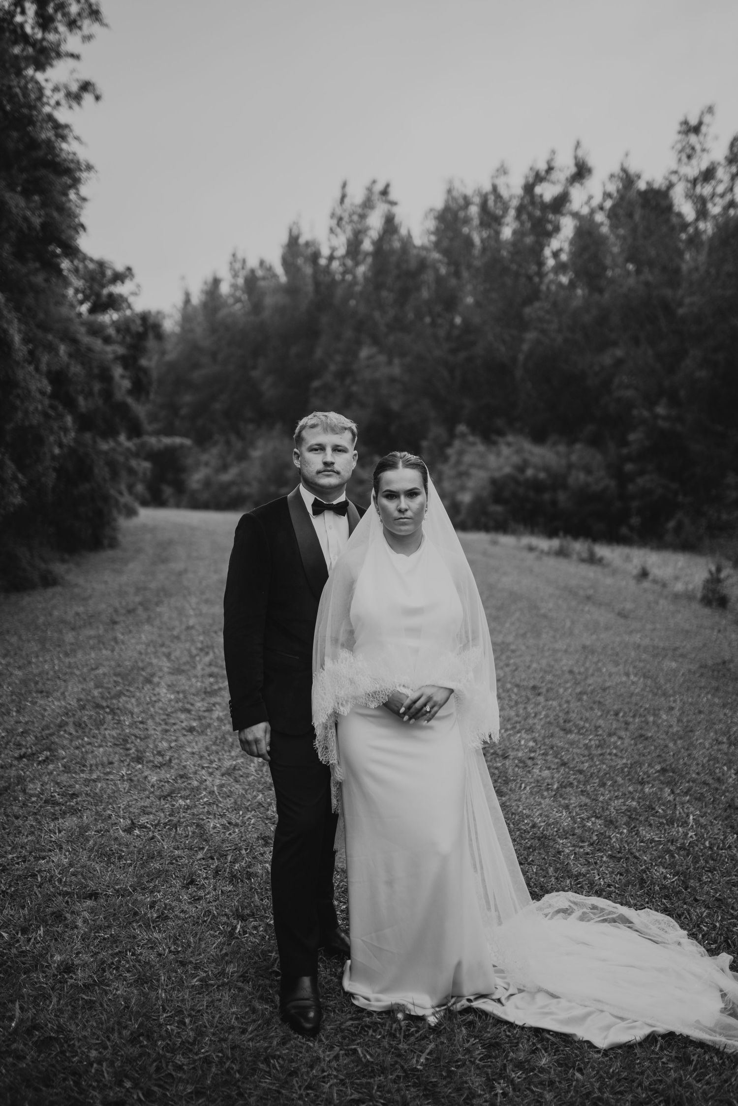A bride and groom share intimate moments together in a field during their wedding photoshoot.