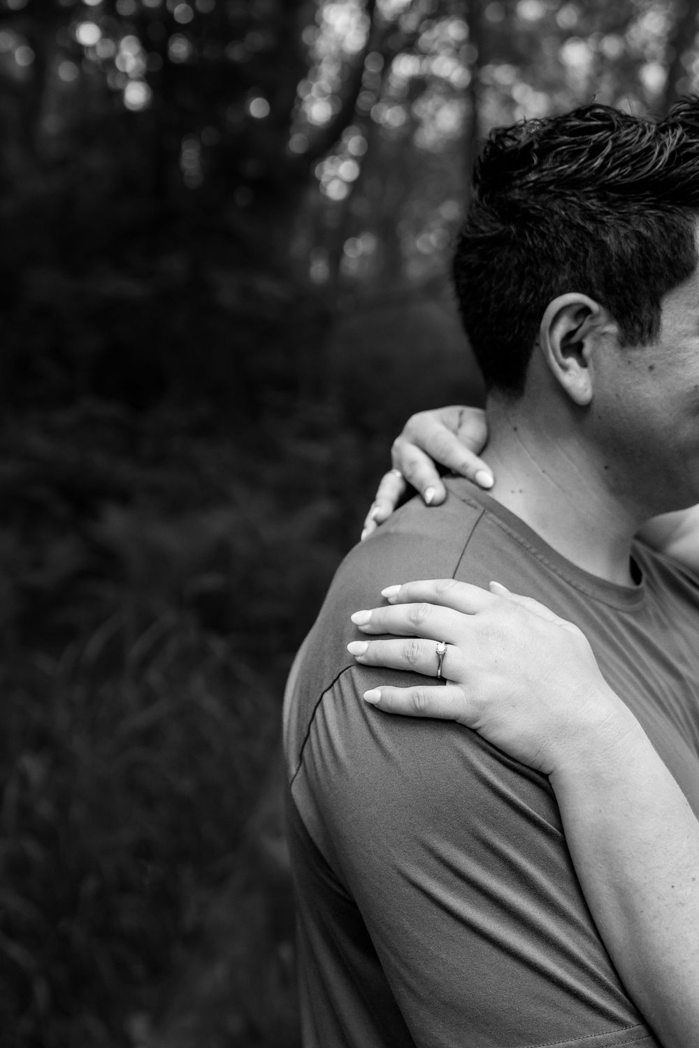 A close-up black and white shot showing hands resting on shoulders.