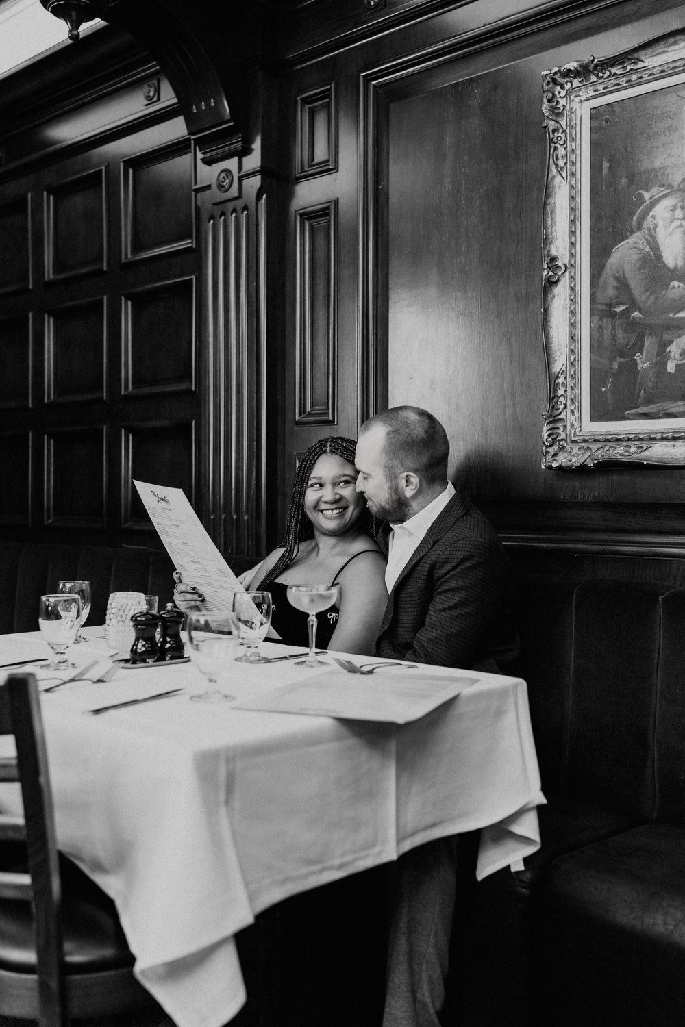 A sequence of black and white photos showing a couple dining at an elegant restaurant with white tablecloths and wood paneling.