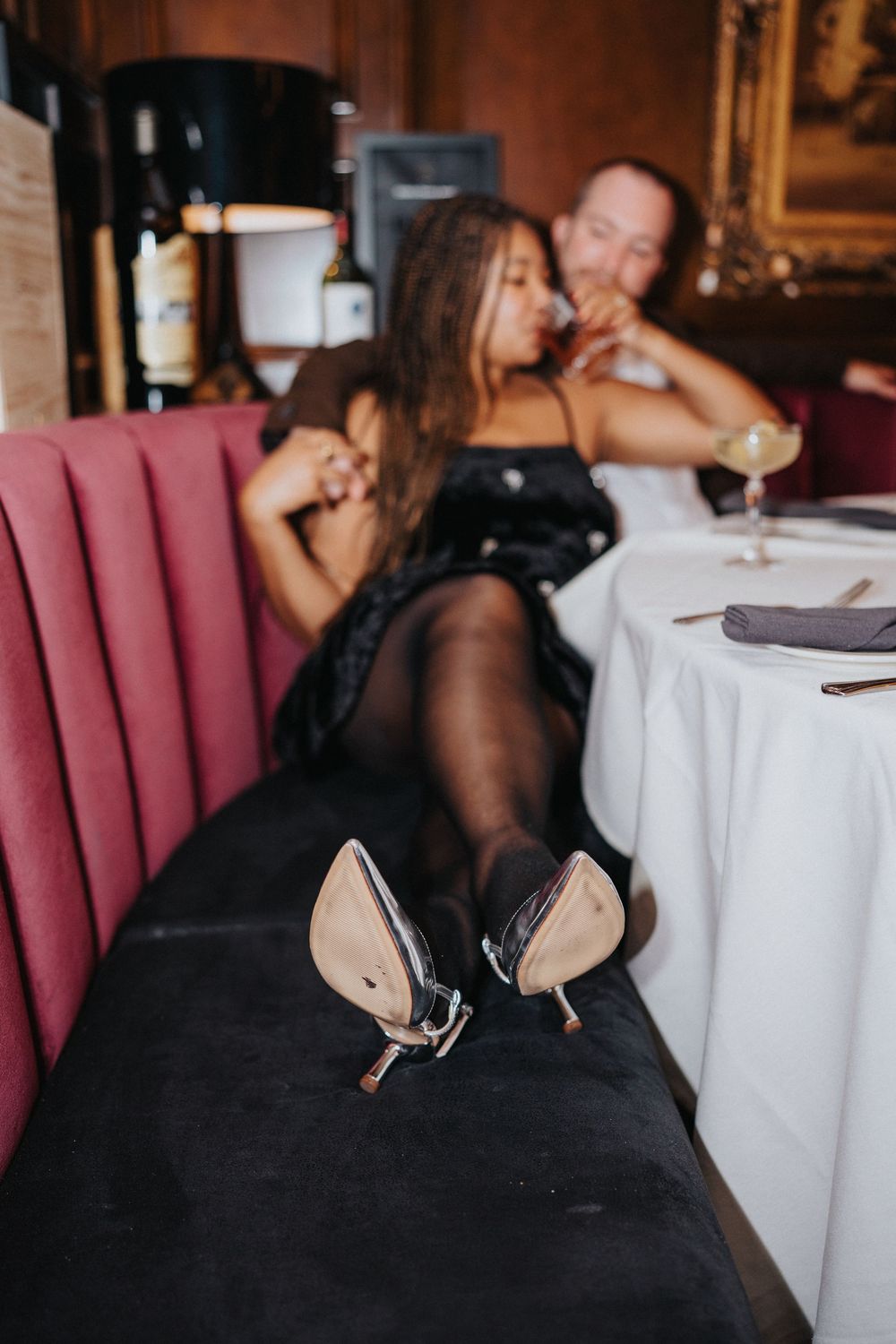 Elegant dinner setting in upscale restaurant with burgundy booth seating and white tablecloths.