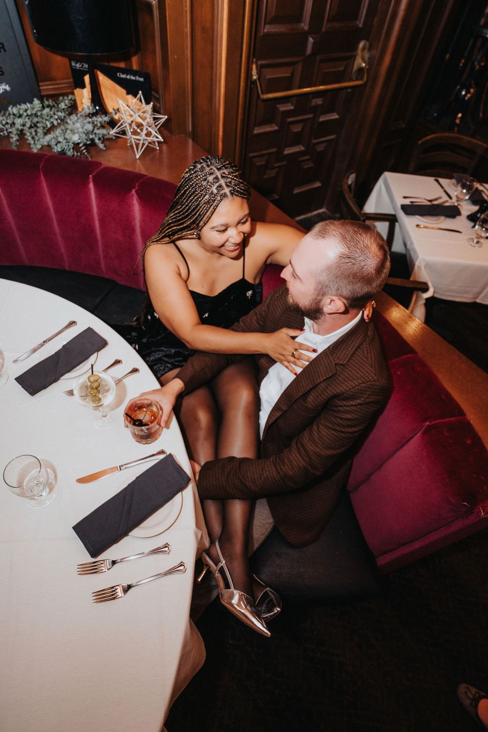 Intimate couple sharing romantic moments at an elegant restaurant table with wine and dining settings.