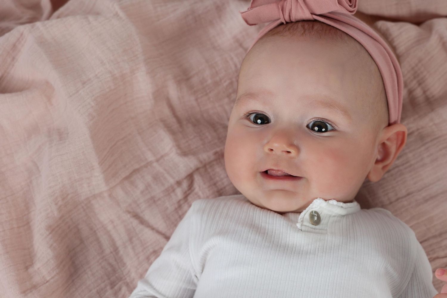 wide eyed infant girl with a pink headband