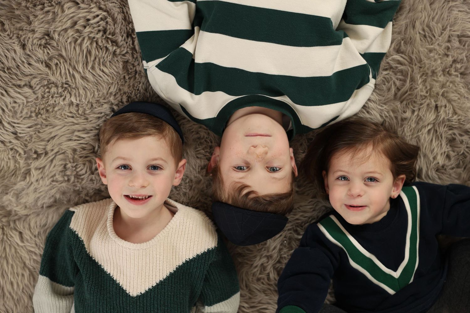 family photo of brothers and sister cuddling on rug in Lakewood, New Jersey photo studio