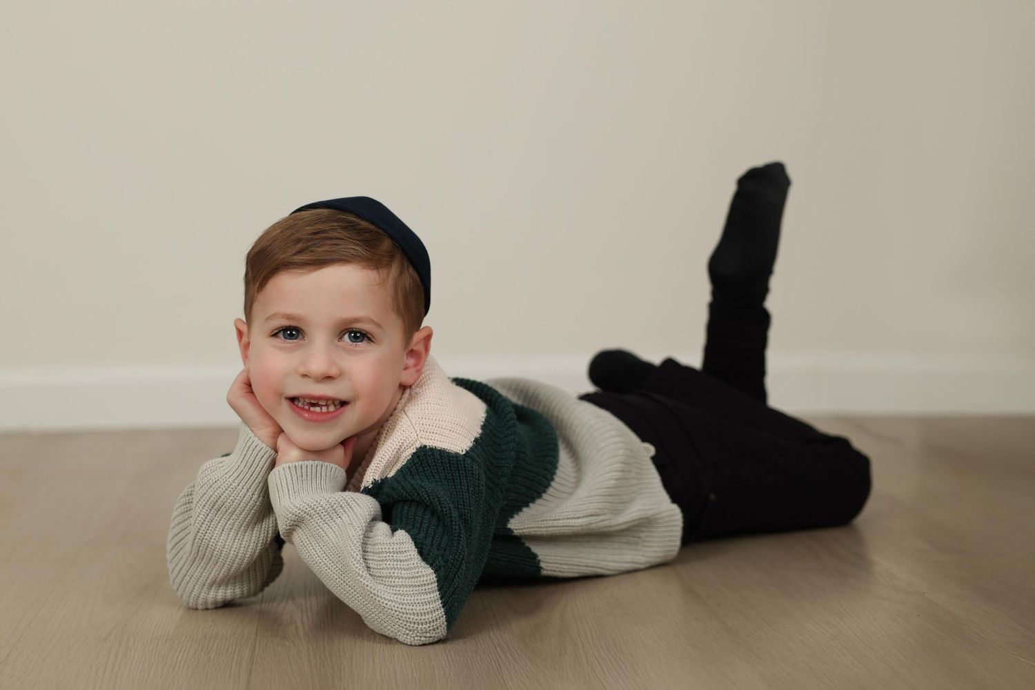 studio portrait of smiling boy with his chin leaning on his hands
