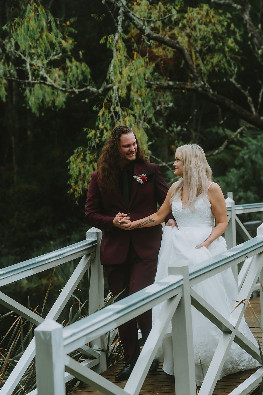 A couple shares a joyful moment together while sitting on a white railing in an outdoor garden setting.