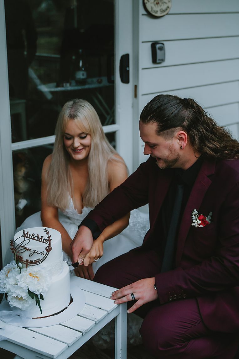 A couple signs their marriage license together at a white table with flowers during their wedding ceremony.