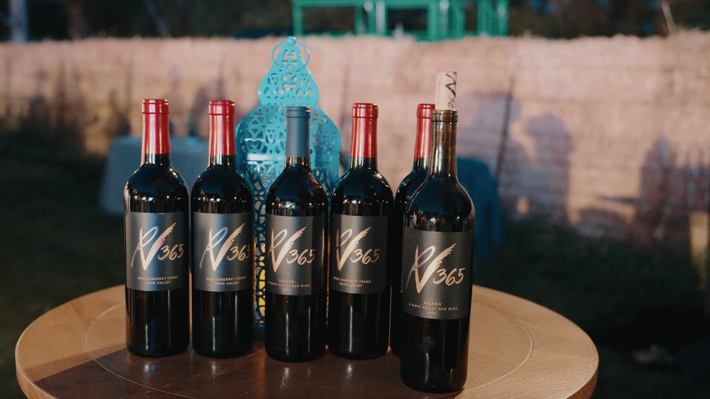 Wine bottles displayed in various settings including shelves, tables and countertops in moody lighting.