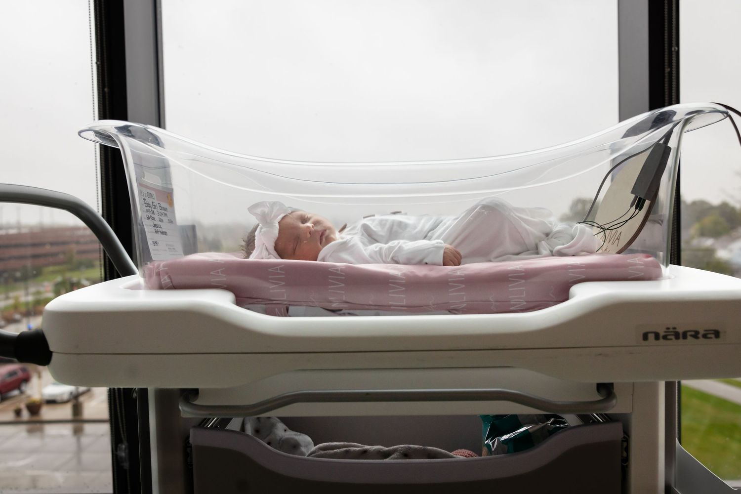 A series of baby changing tables in a nursery room with cribs and storage units arranged in a row.