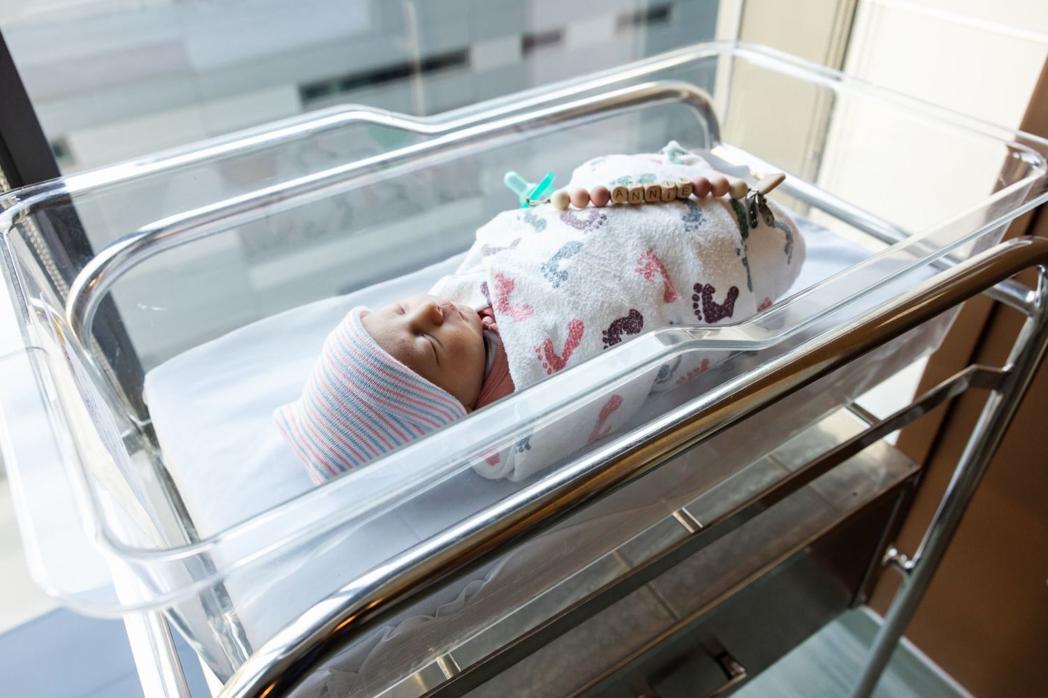 A series of hospital bassinets with newborn babies lined up in a nursery ward.