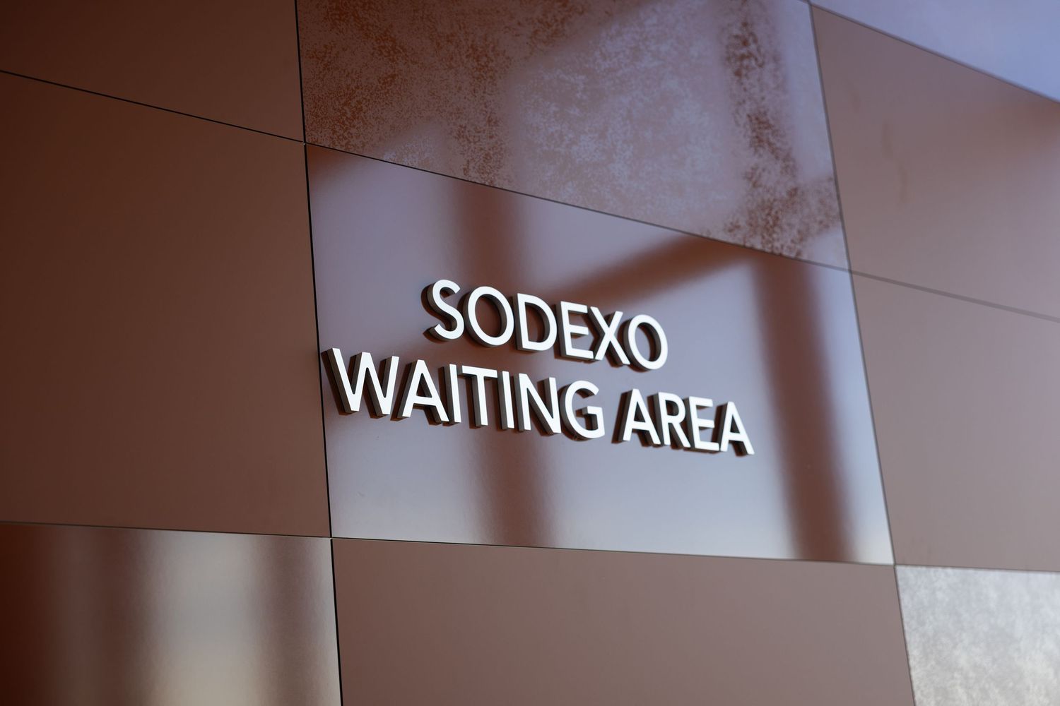 A wall-mounted sign reading 'SODEXO WAITING AREA' in white letters against a modern interior wall.