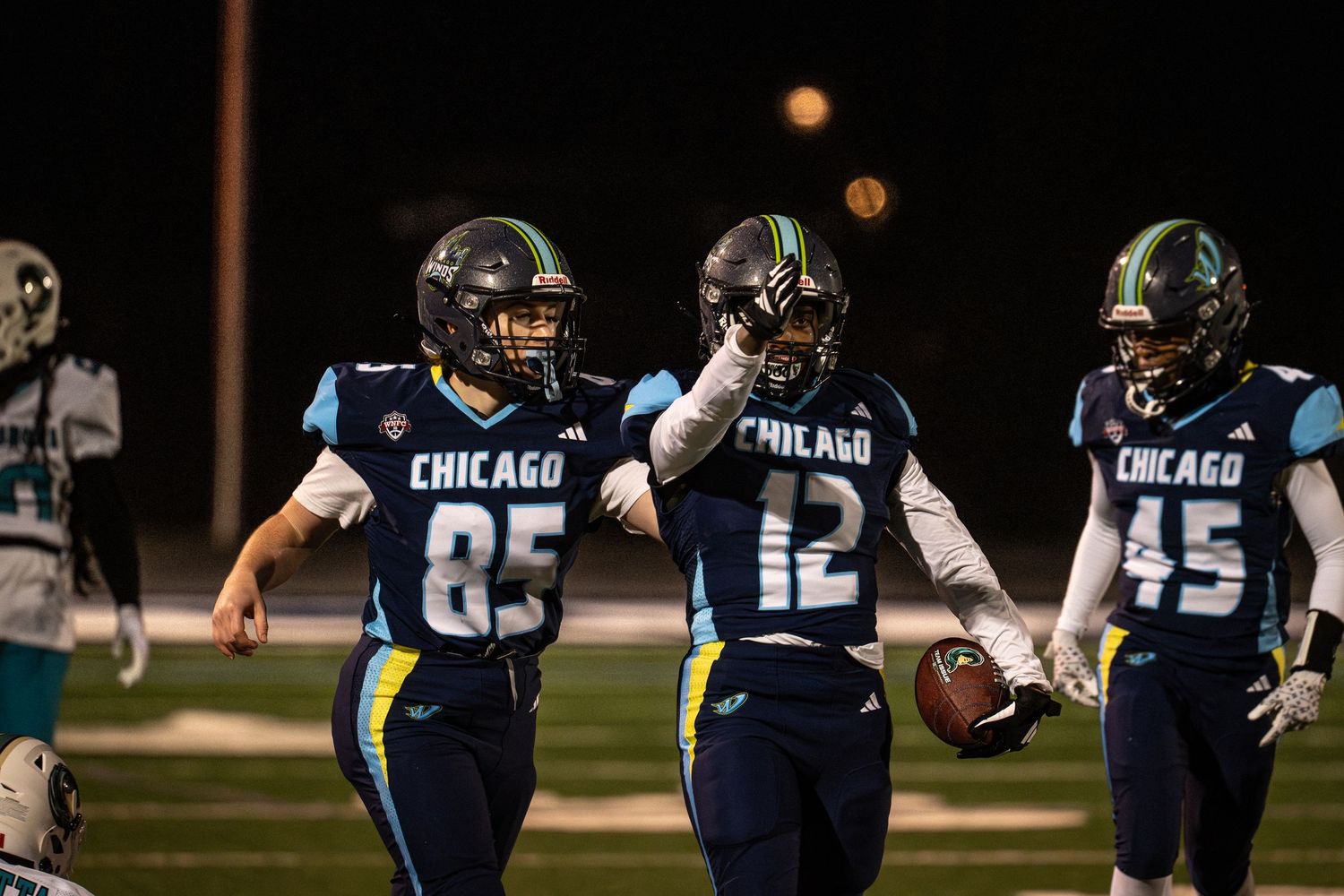 An athlete from the Chicago Winds celebrates a first down by extending their arm forward while teammates cheer them on