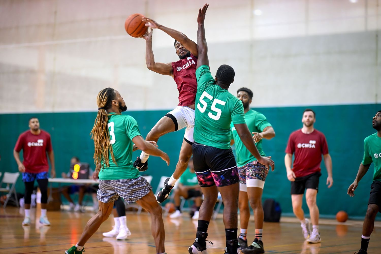 A basketball athlete from CMSA at Broadway Armory attempts to make a bucket but is deflected by a tall defensive player