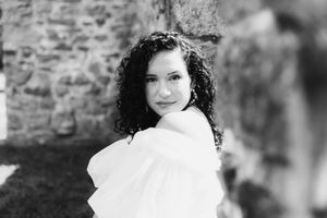 Black and white portrait against weathered stone wall backdrop.