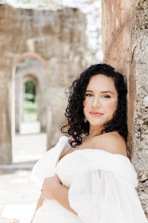 A series of artistic portrait photographs taken in a stone archway featuring someone in a white dress.