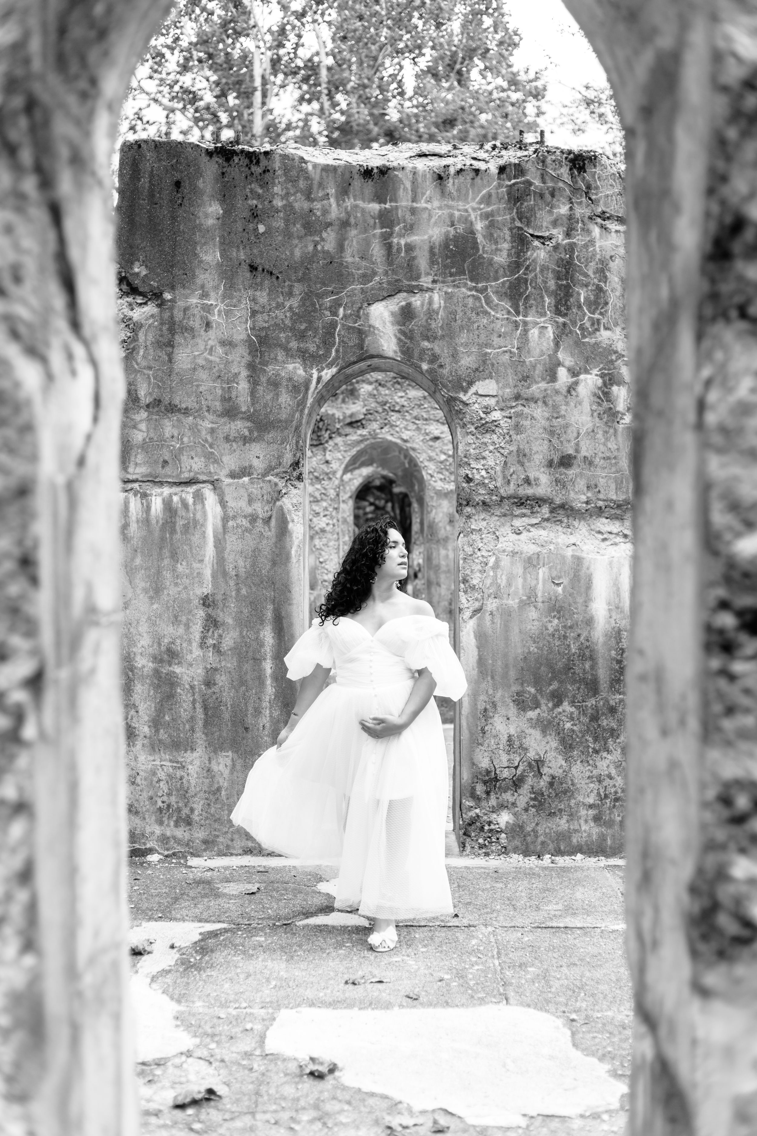 Black and white photo series featuring flowing white dress against historic stone architecture.