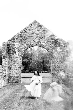 A series of black and white photos showing ethereal figures in flowing white dresses posing in stone archways.
