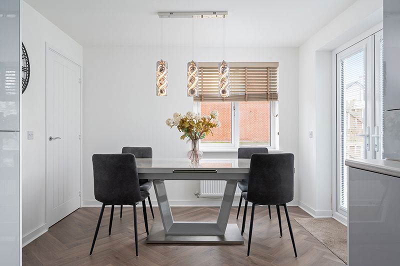 Modern minimalist dining room interior with white walls, black chairs, and bamboo window shades in natural light.