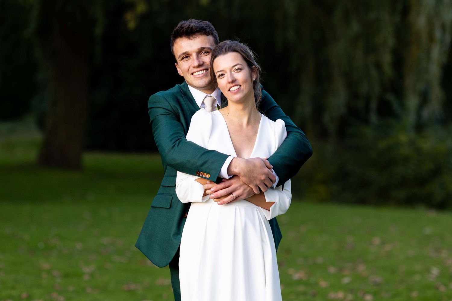 Romantic wedding couple embraces while posing in a lush garden setting.