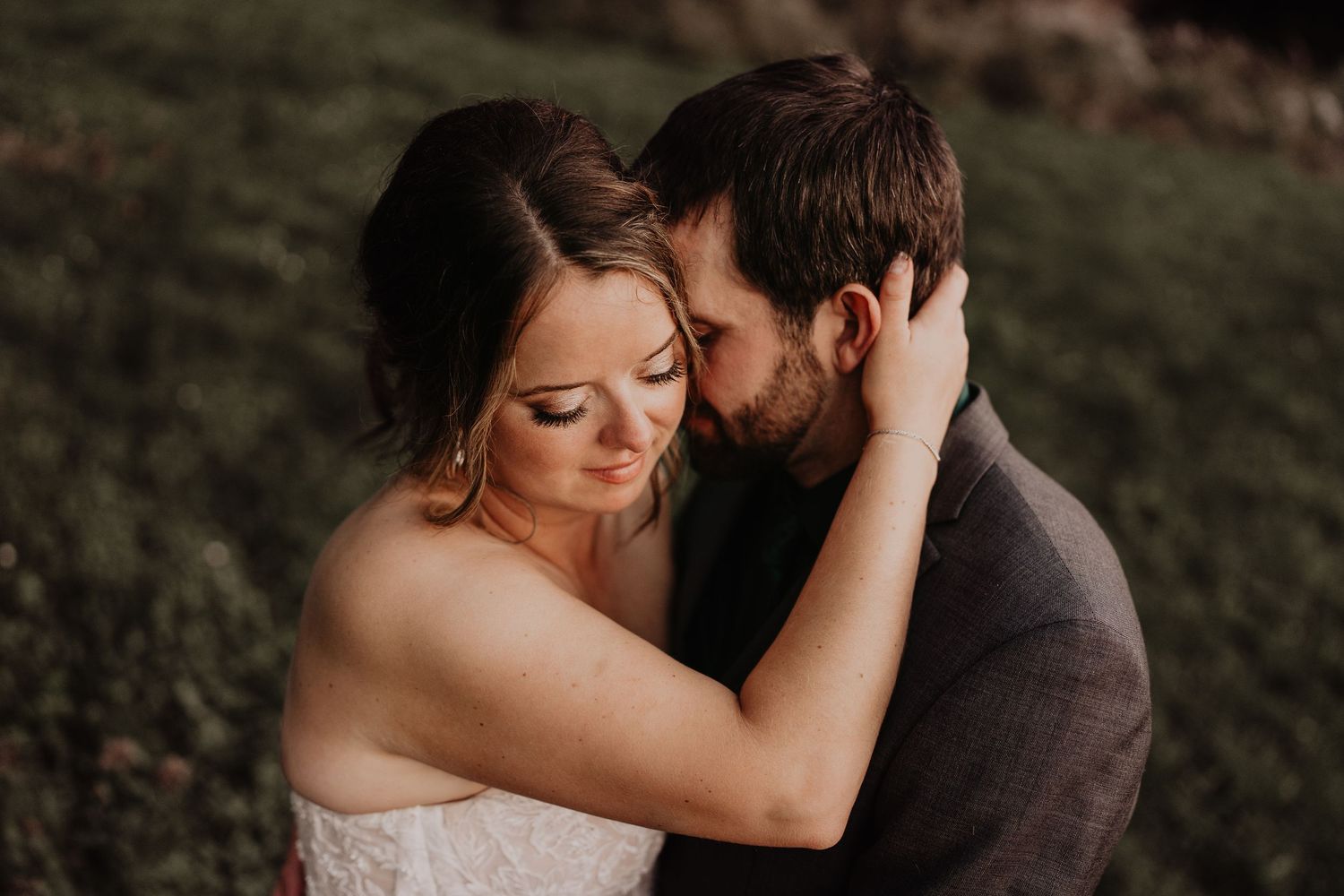 bride and groom embrace with bride's face downturned