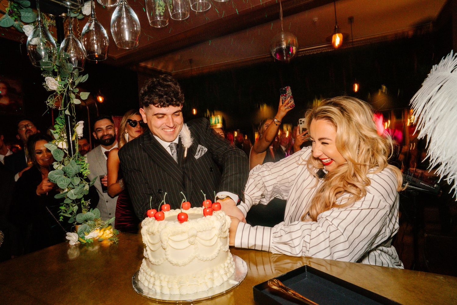 A fun energetic moment of connection and love as Tigs and Fraz cut their wedding cake with red cherries on top