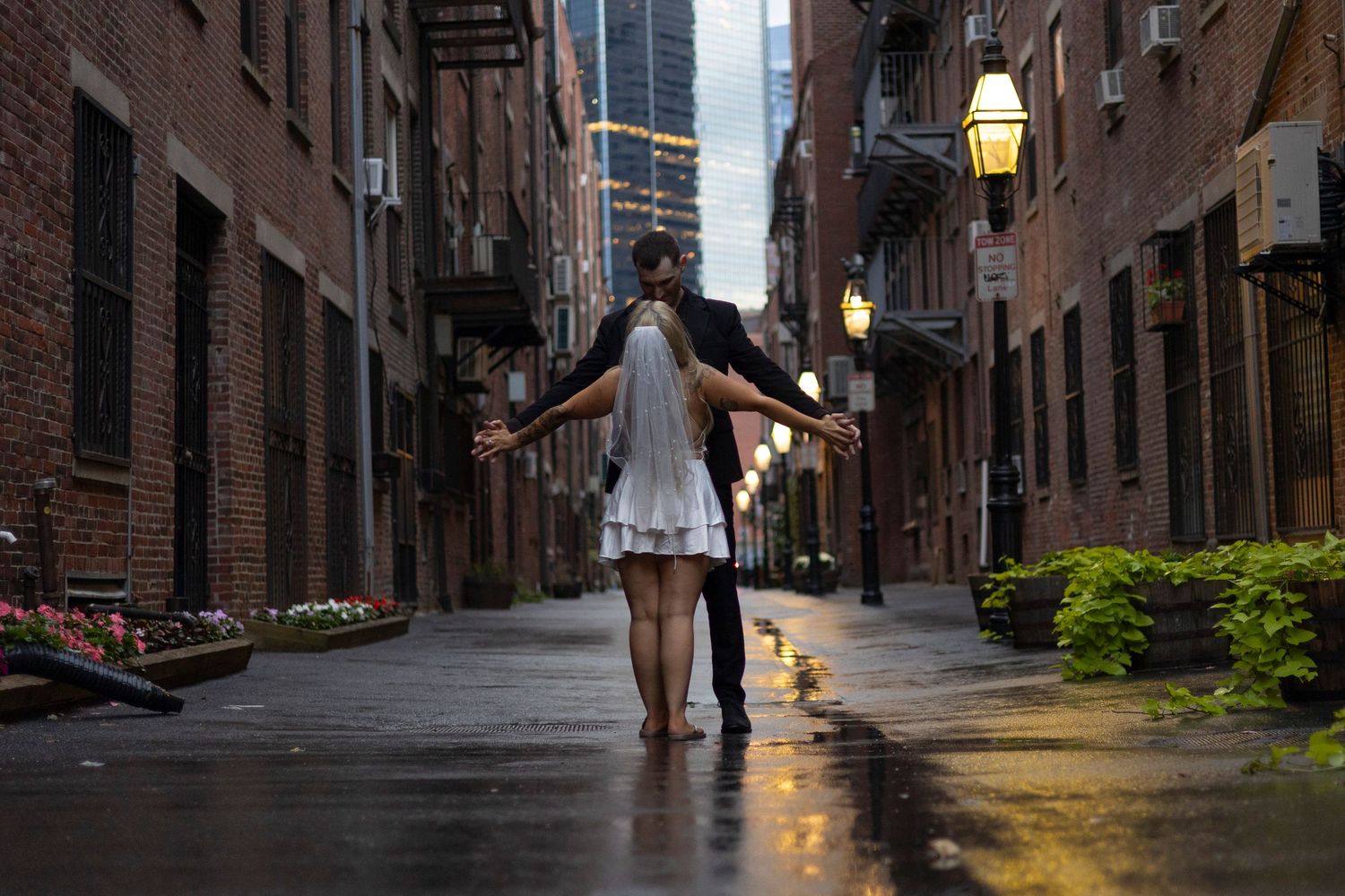 Cobblestone alley with historic brick buildings and lanterns illuminated at dusk in Boston's Beacon Hill neighborhood.