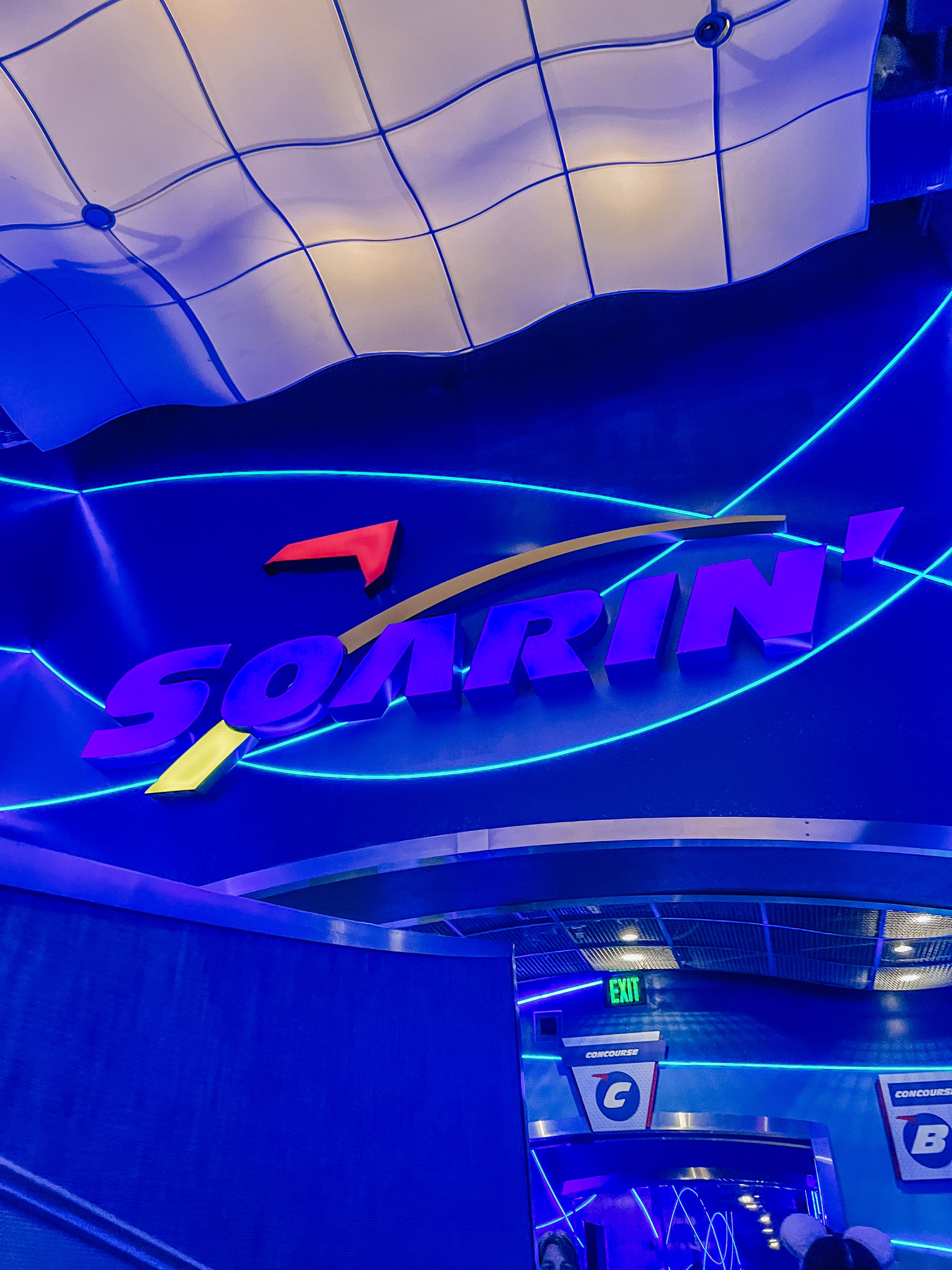 Blue neon lighting elements curve across a dark ceiling creating an atmospheric architectural design feature in an indoor space.