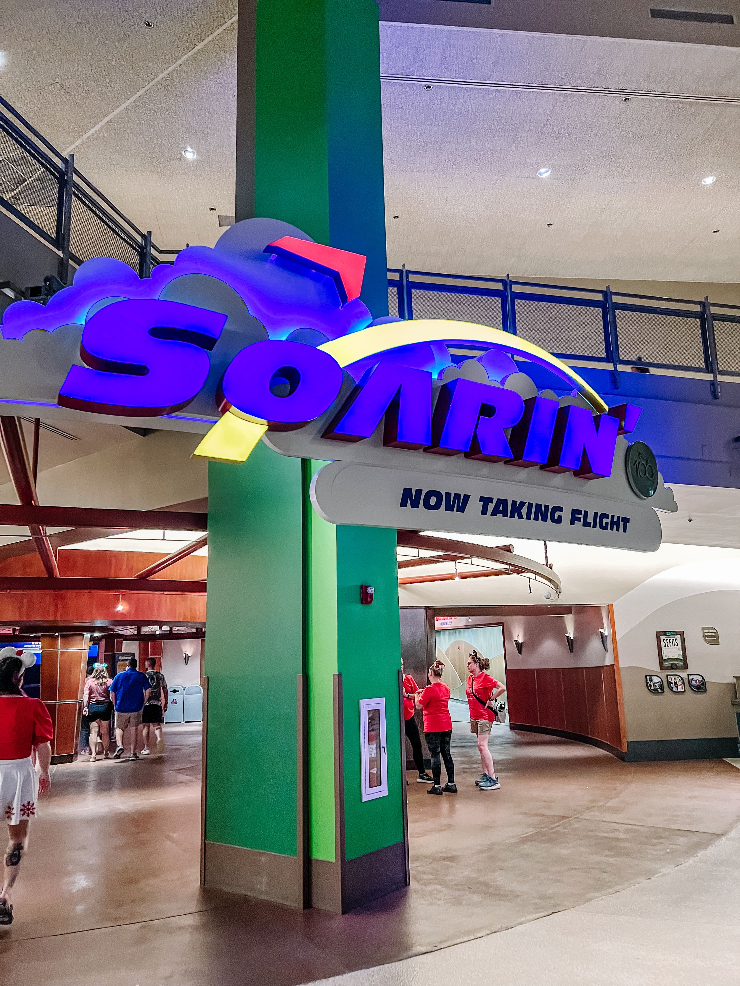 Interior view of an empty mall corridor with retro purple and green architectural elements and directional signage.