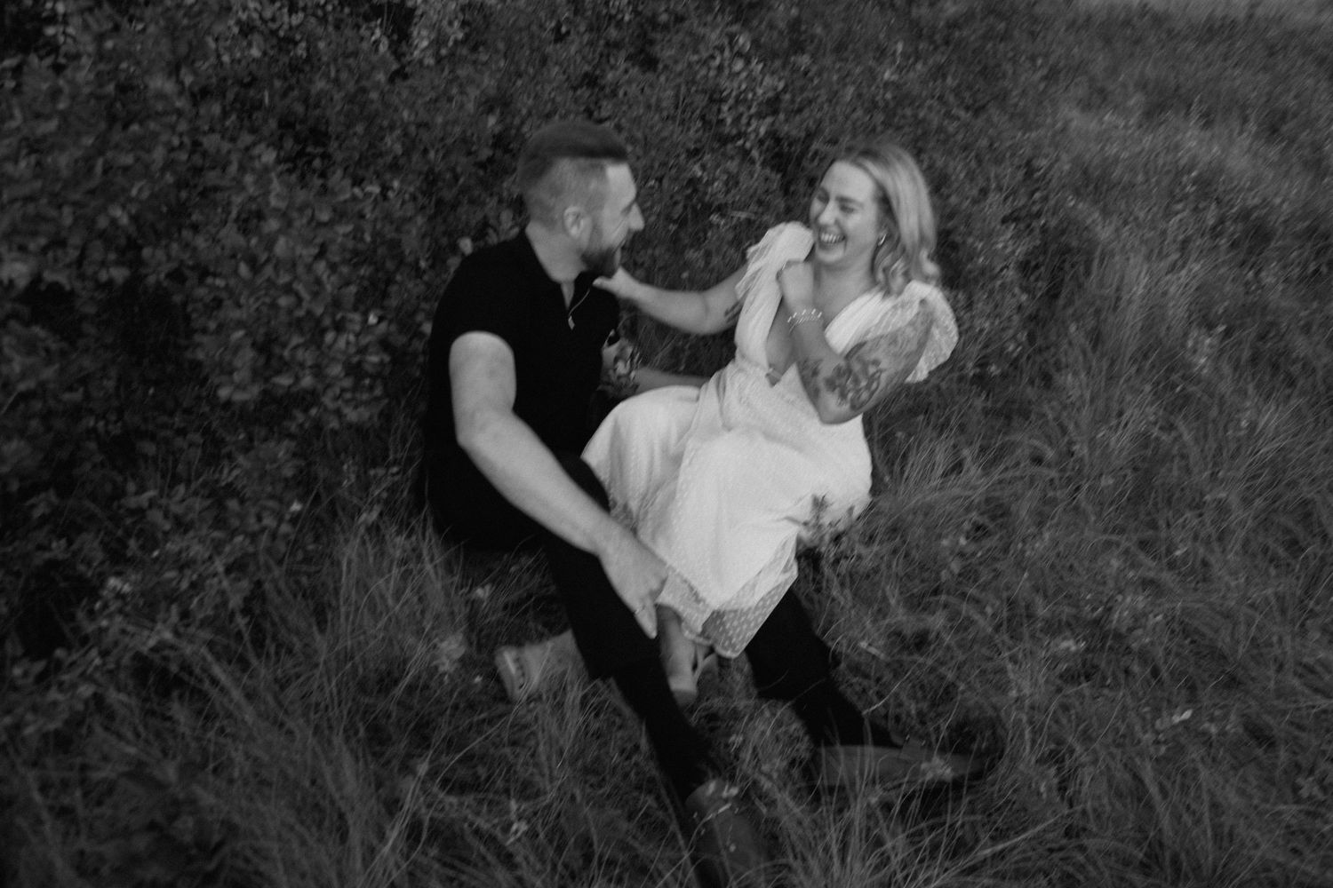 Playful moment captured in black and white photography among tall grass.