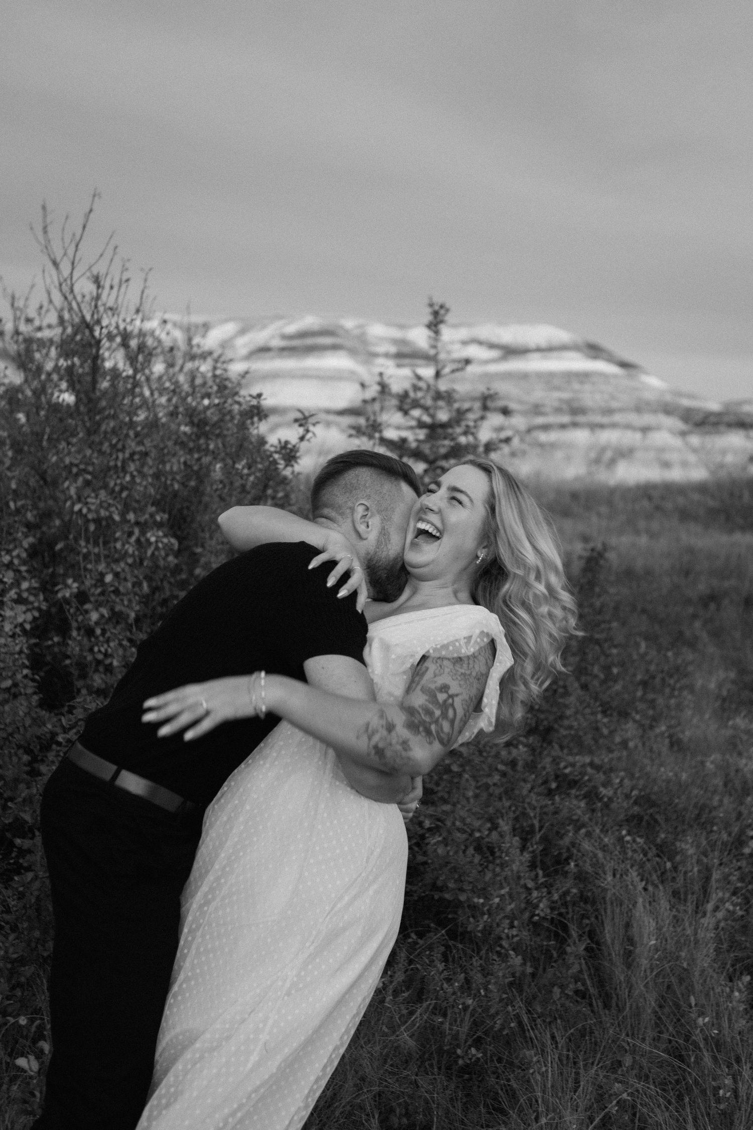 A romantic black and white photo in a mountain landscape with snow-capped peaks in the background.