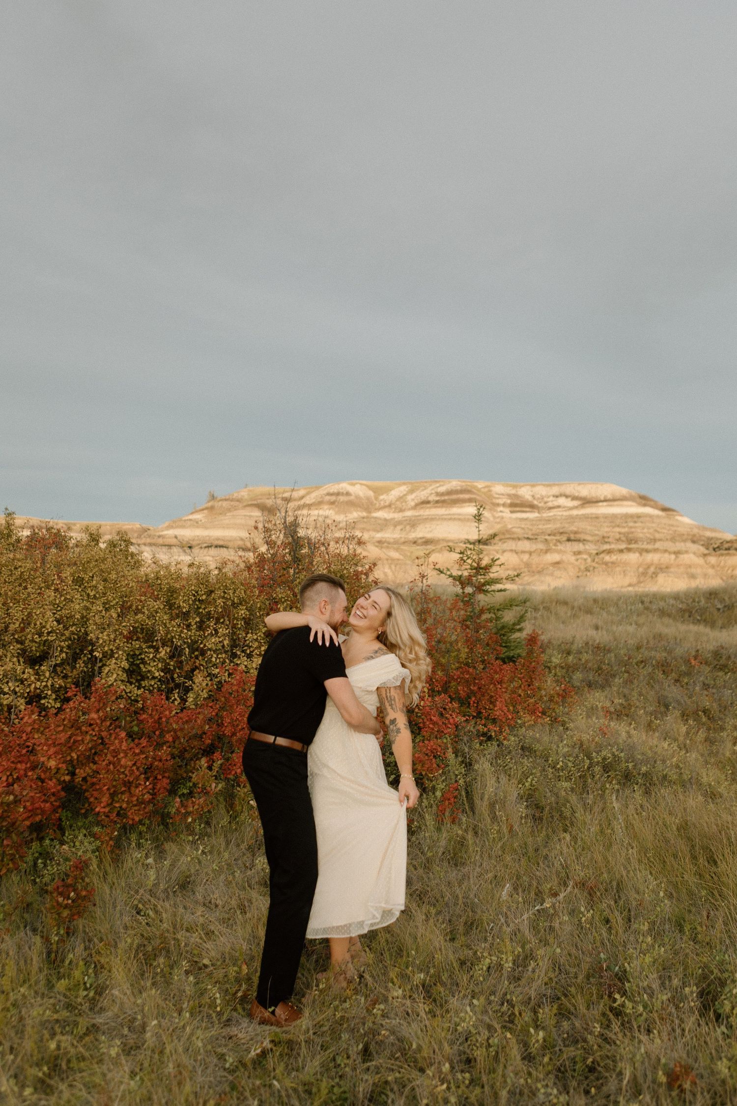 A romantic moment captured against rugged badlands formations during golden hour.
