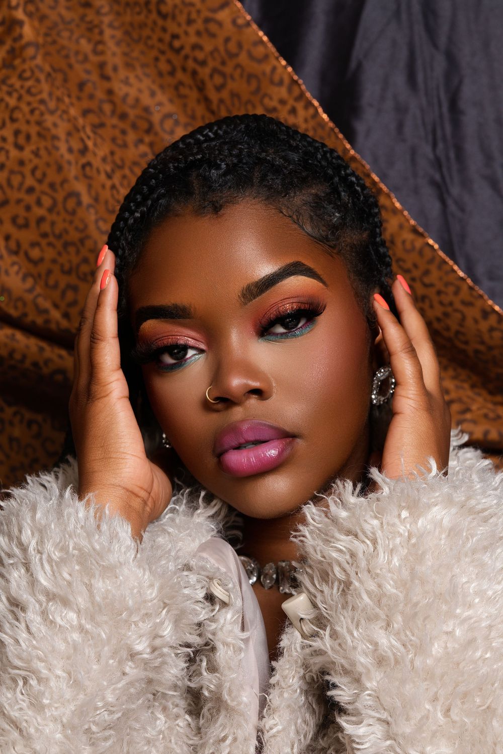 A glamorous beauty portrait featuring dramatic makeup, fluffy white fur, and warm brown leopard print backdrop.