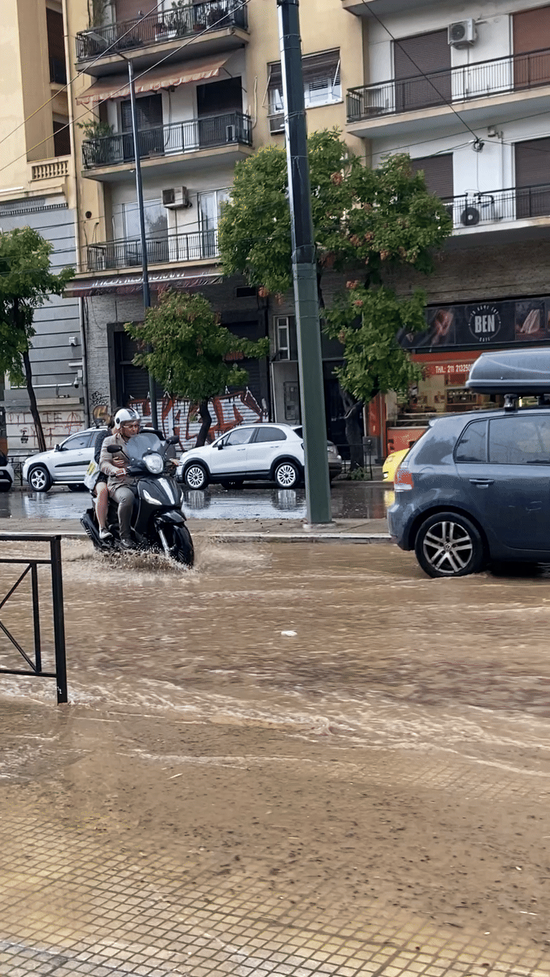 Busy Greek street flooded with rain water.